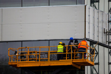 workers on a scaffolding working on the facade of a building