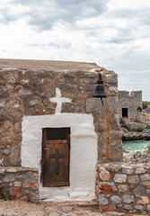 Chapel small with whitewashed framed wooden door, paint cross and hanging old bell. Vertical