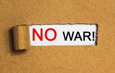 Obraz premium The text NO WAR behind torn brown paper