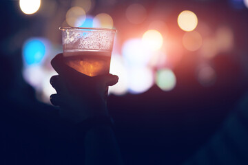 Person holding cold beer plastic cup on a music festival.