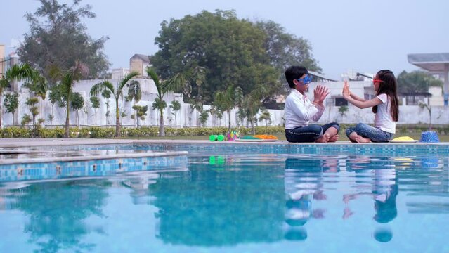A sweet boy and girl playing hand-clapping games - a childhood game  leisure time  a Hindu festival. Cheerful siblings wearing trendy sunglasses celebrating the Indian festival of colors together s...