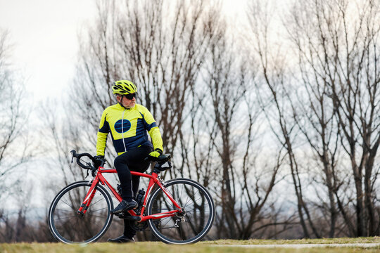 A senior bicyclist on a bike looking behind him.