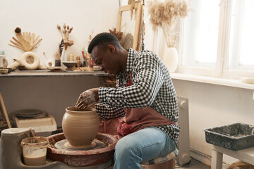 Cheerful man working on new clay vessel