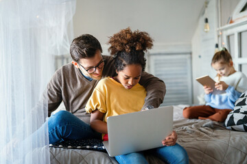 Preteen schoolgirl doing her homework with notebook at home. Child using gadgets to study.