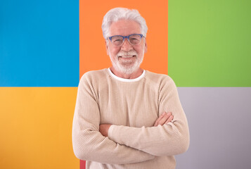 Adult handsome senior man crossed arms looking at camera smiling over colorful cute background....