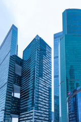 Fototapeta na wymiar The tops of modern corporate buildings in snowfall. Low angle view of skyscrapers.