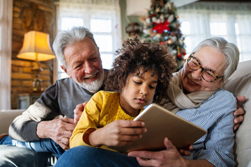Portrait of happy grandparents with child playing together at home