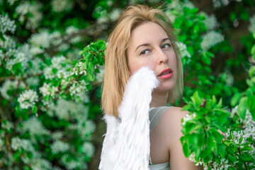 Fototapeta premium Beautiful feminime woman with white wings with white spring flowers.