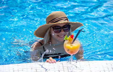 girl drinks a cocktail in the pool.