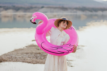 young woman with straw hat has fun inside an inflatable flamingo co