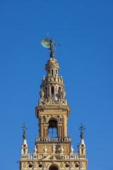 Fototapeta na wymiar The upper part of the Giralda with the Giraldillo. Part of the inscription is visible which says The name of the Lord is a fortified tower