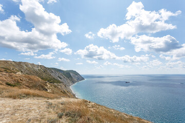 Fototapeta na wymiar Beautiful landscape of high coast, blue sea and fluffy clouds on a sunny summer day. The Black Sea coast. Anapa