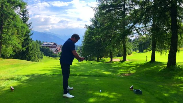 Golfer Teeing Off with Success His 3 Wood on Golf Course with Mountain View in a Sunny Summer Day in Crans Montana, Valais in Switzerland.