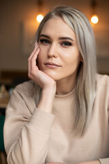 Vertical smiling beautiful attractive blond woman with make up, looking at camera, leaning on hand....