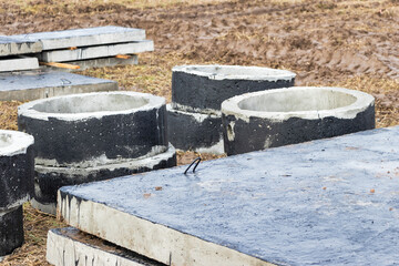 Reinforced concrete rings and slabs for wells on the construction site. Preparation for the device of underground wells and communications. Close-up.