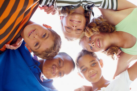 The Future Belongs To Them. Mixed Race Group Of Children Standing In A Circle Looking Down At The Camera.