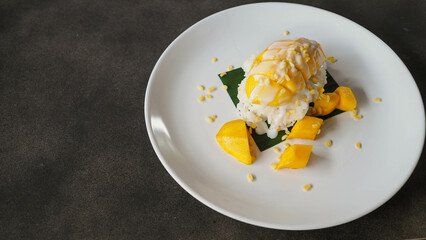 Ripe Mango Sticky Rice with Coconut Milk Authentic Thai desserts, Thai desserts./Mango Sticky Ricein restaurant style in plates with green banana leaves under natural light