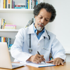 African american senior doctor working at desk