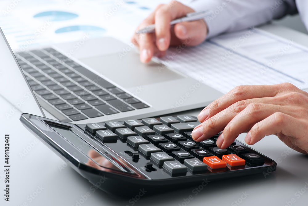 Poster Accounting and calculation. Working with calculator. Close up of hands. Laptop and reports on desk.