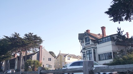 Monterey ocean beach, 17-mile drive, California coast USA. Pacific Grove, beachfront waterfront promenade, waterside historic houses, colonial buildings architecture. Cars on road, cypress pine trees.
