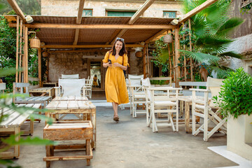 Woman in yellow dress walking by cafe terrace