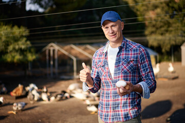 man holding goose egg at poultry farm