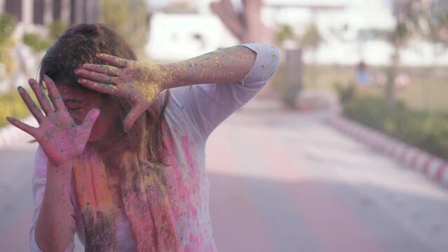 A beautiful Indian lady being smeared with Holi colors while she tries to protect herself - dry colors  organic Gulal. Holi color splash on face - Dry organic colors throw. Festive season  leisure ...