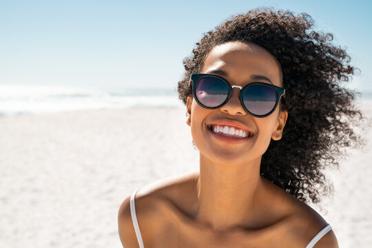 Beautiful black woman at beach wearing sunglasses