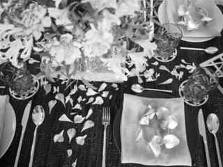 Black and white image of a table setting with flower petals and little garland on dinner plate