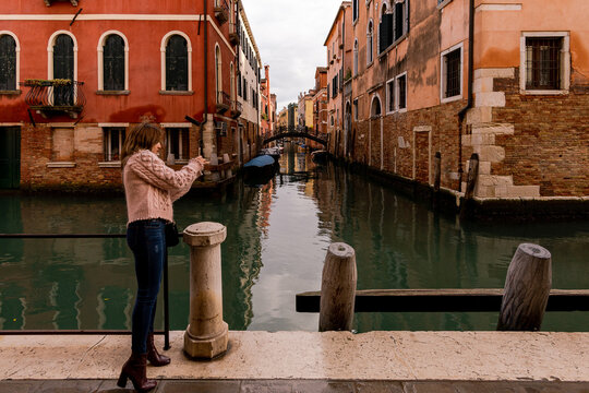 Venice Italy. November 20 2021. Tourist woman taking picture with mobile phone to the canals of Venice