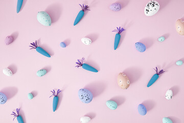 Creative Spring Easter concept on pastel purple background. Painted eggs and carrots for pink note or invitation. Flat lay.