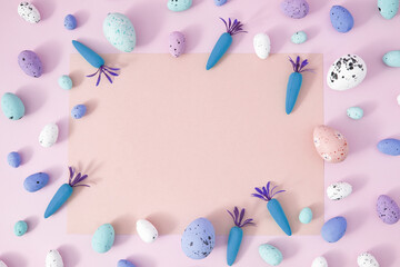 Creative Spring Easter concept on pastel purple background. Painted eggs and carrots with copy space for note or invitation. Flat lay.