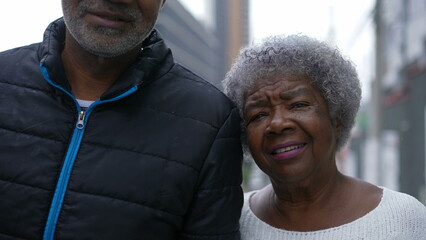 A son and senior mother walking together in street 80s parent