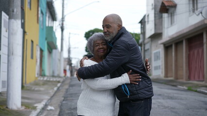 A Brazilian son embracing a senior mother in 80s outside portrait