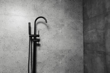Black freestanding bath taps, on the background of dark grey bathroom walls.