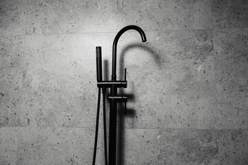 Black floor-standing bath taps, on the background of dark grey bathroom walls.