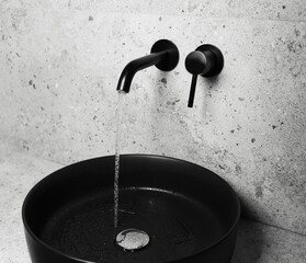 Photo of bathroom details: black sink and faucet with flowing water.