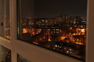 Fototapeta na wymiar Admiring night view of the city and its night lights, from the window.
