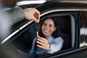 Happy woman getting a key for a new car, looking exiting.