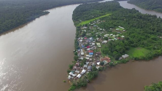 Aerial drone footage flying over remote village alongside the river in South America.