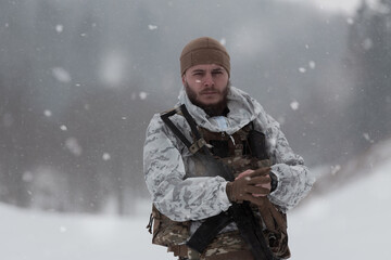 Soldier in winter camouflaged uniform in Modern warfare army on a snow day on forest battlefield...