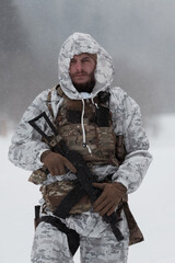 Soldier in winter camouflaged uniform in Modern warfare army on a snow day on forest battlefield...