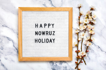 Obraz na płótnie Canvas Sprigs of the apricot tree with flowers and Text Happy Nowruz Holiday Concept of spring came Top view Flat lay Hello march, april, may, persian new year