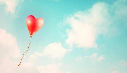 Fototapeta na wymiar Red heart shaped balloon in a blue sky vintage style background
