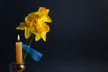 Pray for Ukraine. Burning candle, yellow flowers and blue ribbon. Stop war 2022.