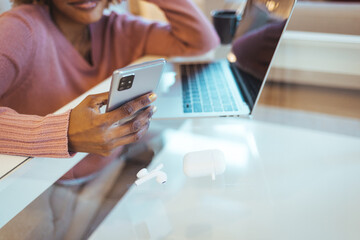 Close up of a woman using a phone. Close up on a young woman using smartphone and laptop at the home. Updating the business social media page