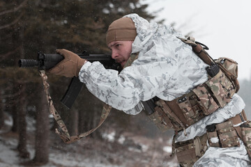 Soldier in winter camouflaged uniform in Modern warfare army on a snow day on forest battlefield...