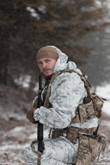 Soldier in winter camouflaged uniform in Modern warfare army on a snow day on forest battlefield with a rifle. Model face very similar to Ukraine prime minister.