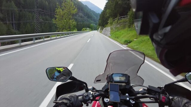 POV of Biker rides a motorcycle on a scenic mountain road in Austria. Steering wheel view. Motorcyclist on Motorbike goes on a Beautiful landscape highway. First-person view. Solo motorcycle travel.