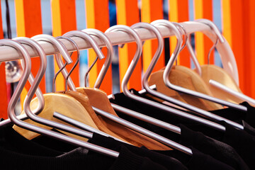 Aluminum and wooden hangers on a metal rack. Trade in clothes in a small showroom. selective focus